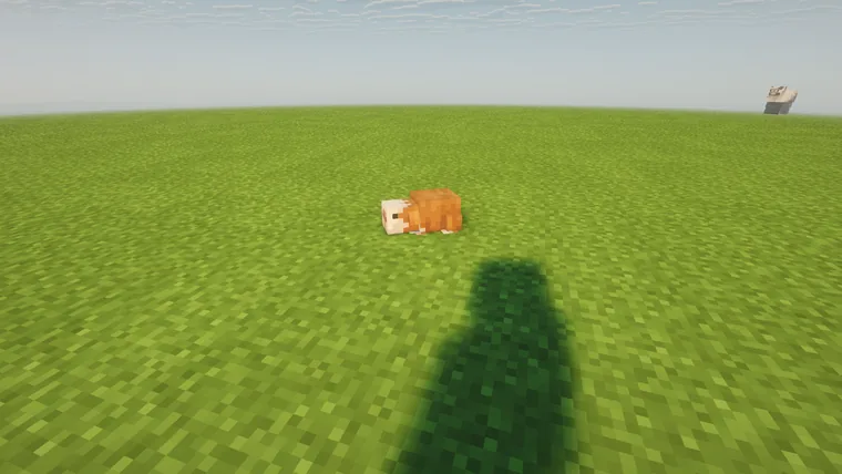 A capybara resting on open grassland under a clear sky.